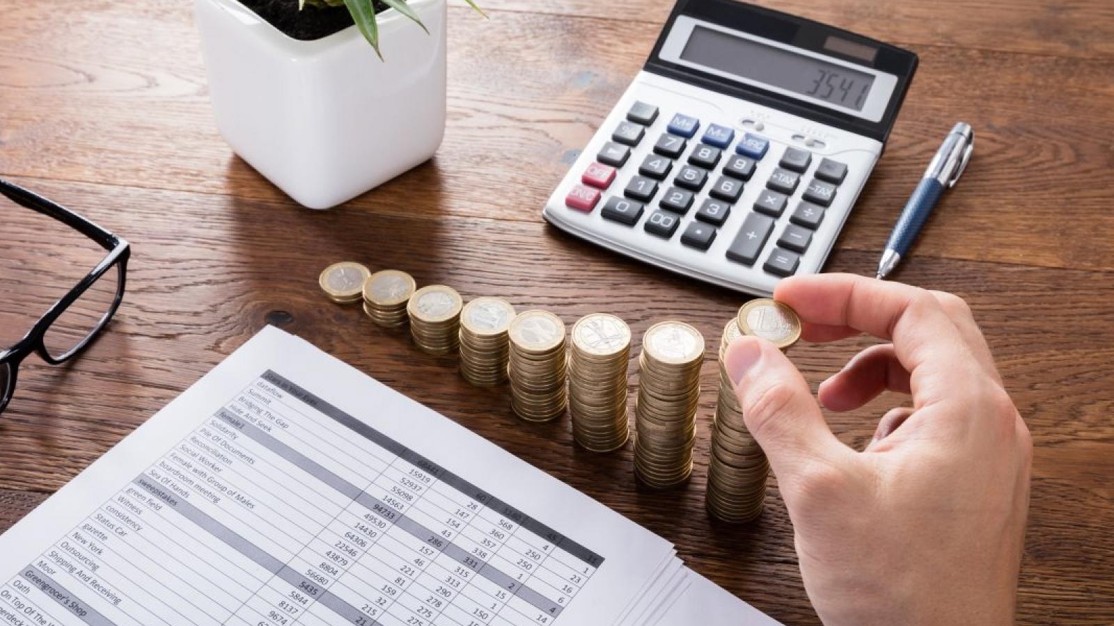 Person Stacking Coins On Desk